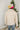 Back view of model wearing the New Adventure Puffer Jacket in Cream that has a cream nylon material, a puffer design, a long sleeve, a zip-up front, and front pockets. 