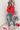 Full body Front view of model wearing the he Holiday Spirit Mock Neck Sweater that has red fabric with open knit details, a mock neckline, dropped shoulders, long sleeves, and ribbed trim.