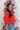 Side view of model wearing the he Holiday Spirit Mock Neck Sweater that has red fabric with open knit details, a mock neckline, dropped shoulders, long sleeves, and ribbed trim.