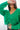 Close front view of model wearing the Merry And Bright Sweater that has green knit fabric, a cropped waist, a ruched drawstring front, a v neckline, and long balloon sleeves.