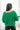 Back view of model wearing the Merry And Bright Sweater that has green knit fabric, a cropped waist, a ruched drawstring front, a v neckline, and long balloon sleeves.
