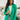 Front view of model wearing the Business As Usual Blazer in Green that has a green material with a full lining, a lapel and a collar, shoulder pads, cuffed sleeves, and faux front pockets. Worn over white top.