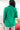 Back view of model wearing the Business As Usual Blazer in Green that has a green material with a full lining, a lapel and a collar, shoulder pads, cuffed sleeves, and faux front pockets. Worn over white top.