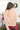 Back view of model wearing the No Plans Pullover in Pink that has light pink waffle-knit fabric, long batwing sleeves, a hood with an ivory drawstring, and a wide fit