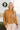 Front view of model wearing the No Plans Pullover in Brown that has light brown waffle-knit fabric, long batwing sleeves, a hood with an ivory drawstring, and a wide fit