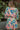 Back view of model wearing the Look On The Bright Side Dress that has a pink, green, blue, yellow and cream flower pattern, a mini-length hem, an elastic waist with a tie, a surplice neck, and long balloon sleeves.