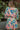 Back view of model wearing the Look On The Bright Side Dress that has a pink, green, blue, yellow and cream flower pattern, a mini-length hem, an elastic waist with a tie, a surplice neck, and long balloon sleeves.