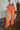 Front view of model wearing the Pop Of Color Pants that feature orange fabric, side pockets, a front zipper with a hook closure, and wide legs with pleated details.