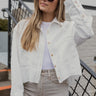 Front view of model wearing the On Your Own Corduroy Shacket that has white corduroy, a cropped waist with a raw hem, a button-up front, front chest pockets, and long sleeves. Worn over white tank.