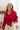 Front view of model wearing the Bristol Oversized Satin Top in Red that has red satin fabric, a button-up front with a collared neckline, one chest pocket, long sleeves with buttoned cuffs, and an oversized fit Shown tied up.