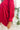Close side view of model wearing the Bristol Oversized Satin Top in Red that has red satin fabric, a button-up front with a collared neckline, one chest pocket, long sleeves with buttoned cuffs, and an oversized fit