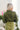 Back view of model wearing the Love Letter Cropped Satin Top that has olive green satin fabric, a collared surplice neckline with a snap closure, a cropped waist with an elastic back, and long sleeves with buttoned cuffs.