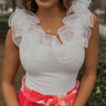 Close up view of model wearing the Meant To Be Ruffle Bodysuit which features white ribbed fabric, a round neckline, sheer ruffle details, a sleeveless body, and a thong bottom with snap closures.