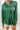 Close up view of model wearing the Fancy Me Satin Top in Green which features emerald green satin fabric, a button-up front with a collared neckline, one chest pocket, and long sleeves with buttoned cuffs.