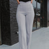 Front view of model wearing the Let's Chat Pants in Grey that have light grey fabric, exposed seams down the front legs, a v-shaped waist, a back zipper, and flared legs.