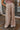 Front view of model wearing the Keep It Classic Pants that have khaki colored fabric, two front pockets, a front zipper and hook closure, belt loops, and wide legs with pleated details.