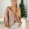 Front view of model wearing the Bristol Oversized Satin Top in Mocha that has light brown satin fabric, a button-up front with a collar, one chest pocket, long sleeves with buttoned cuffs, and an oversized fit. 