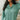 Front view of model wearing the Spot On Satin Top in Jade that has light teal satin fabric with a monochromatic spot print, a button-up front with a collar and lapels, and long sleeves with buttoned cuffs