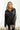 Front view of model wearing the Bristol Oversized Satin Top in Black that has black satin fabric, a button-up front with a collar, one pocket and long sleeves. 