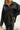 Close front view of model wearing the Aria Oversized Satin Top in Black that has black satin fabric, a button-up front with a collar, one pocket and long sleeves.