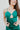 close-up front view of model wearing the Life Of The Party Maxi Dress which has an emerald green satin material, a deep open neckline, thin adjustable straps, a side drape detail with a slit, an open back, and a back zipper closure.