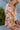 Side view of model wearing the Hopeless Romantic Floral Top, which features a silky material, a multi-colored floral print, a notched neckline with a ruffle detail, long sleeves, and a flowy fit