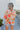 Back view of model wearing the Hopeless Romantic Floral Top, which features a silky material, a multi-colored floral print, a notched neckline with a ruffle detail, long sleeves, and a flowy fit