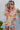 Front view of model wearing the Hopeless Romantic Floral Top, which features a silky material, a multi-colored floral print, a notched neckline with a ruffle detail, long sleeves, and a flowy fit