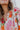 Close-up view of neckline - model is wearing the Hopeless Romantic Floral Top, which features a silky material, a multi-colored floral print, a notched neckline with a ruffle detail, long sleeves, and a flowy fit