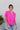 Front view of model wearing the Irreplaceable Top In Pink, which features a hot pink material, a round neckline with a ruffle detail, a cut-out at the chest with adjustable ties, a short smocked sleeve, and a flowy fit