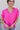 Front view of model wearing the Irreplaceable Top In Pink, which features a hot pink material, a round neckline with a ruffle detail, a cut-out at the chest with adjustable ties, a short smocked sleeve, and a flowy fit