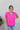 Front view of model wearing the Irreplaceable Top In Pink, which features a hot pink material, a round neckline with a ruffle detail, a cut-out at the chest with adjustable ties, a short smocked sleeve, and a flowy fit