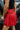 Sideview of model wearing the Game On Shorts, which feature a red shimmer material, a smocked waist, a high-rise fit, a ruffle top hem, and a flowy fit.