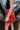 Side view of model wearing the Game On Shorts, which feature a red shimmer material, a smocked waist, a high-rise fit, a ruffle top hem, and a flowy fit.