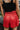 Back view of model wearing the Game On Shorts, which feature a red shimmer material, a smocked waist, a high-rise fit, a ruffle top hem, and a flowy fit.
