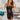 Frontal view of the Icon Mini Dress that features a black colored PU material, a straight neckline, a sleeveless design, a small front slit, and a hidden back zipper.