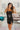 Frontal view of the Icon Mini Dress that features a black colored PU material, a straight neckline, a sleeveless design, a small front slit, and a hidden back zipper.