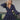 Frontal view of the On The Spot Mini Dress that features a navy colored material, a deep V neckline, a long cuffed sleeve, side cut-outs, a tiered design, a back tie closure, an open back, and a mini length.