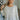 Frontal view of the Easy Breezy Top that features a cream colored knit material, an open knit design, a V neckline, a long cuffed sleeve, side slits, and a high-low design.