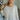 Frontal view of the Easy Breezy Top that features a cream colored knit material, an open knit design, a V neckline, a long cuffed sleeve, side slits, and a high-low design.
