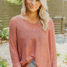 Frontal view of the Easy Breezy Top that features a pink colored knit material, an open knit design, a V neckline, a long cuffed sleeve, side slits, and a high-low design.