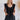 Frontal view of the End Game Romper that features a black cotton material, a rounded v neckline, a sleeveless design with tick straps, ruffle details at the straps, side pockets, a shorts bottom, a tie back, and a flowy fit.