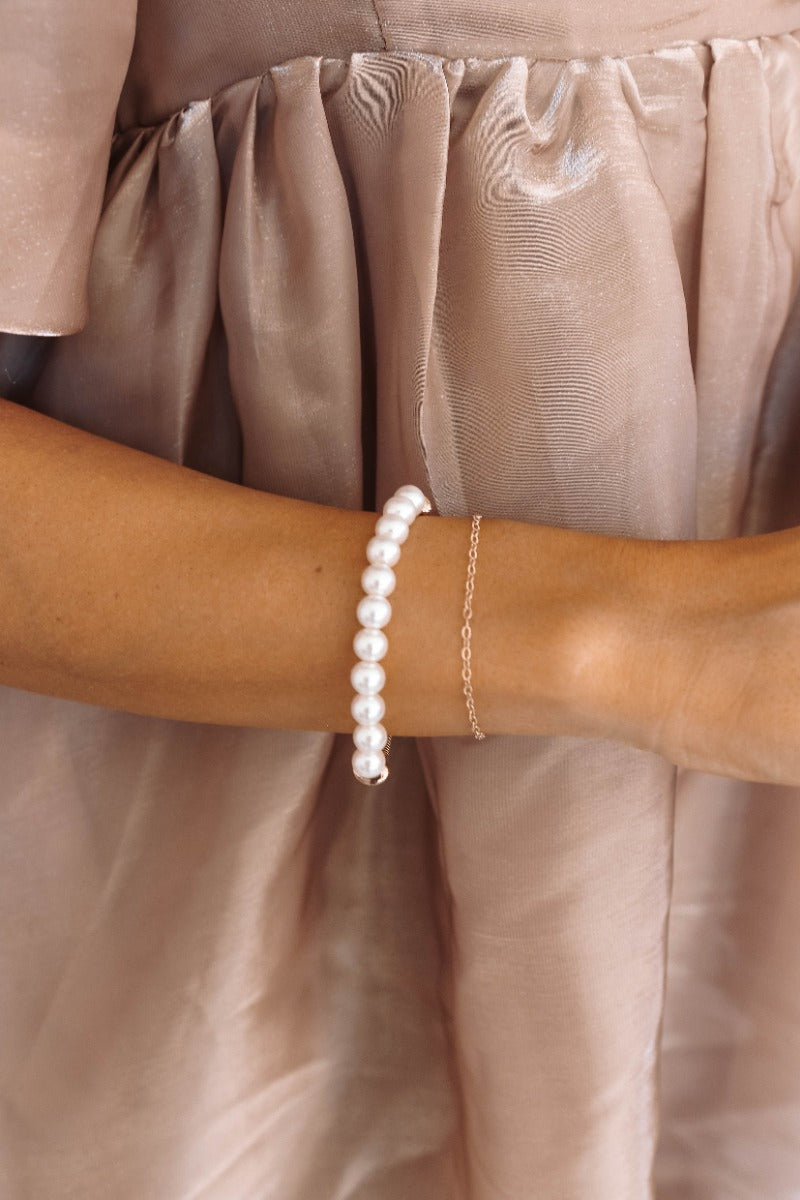 Image of model wearing the Imani Pearl & Gold Bracelet that features a stretchy gold band with faux pearl beads.
