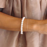 Image of model wearing the Imani Pearl & Gold Bracelet that features a stretchy gold band with faux pearl beads.
