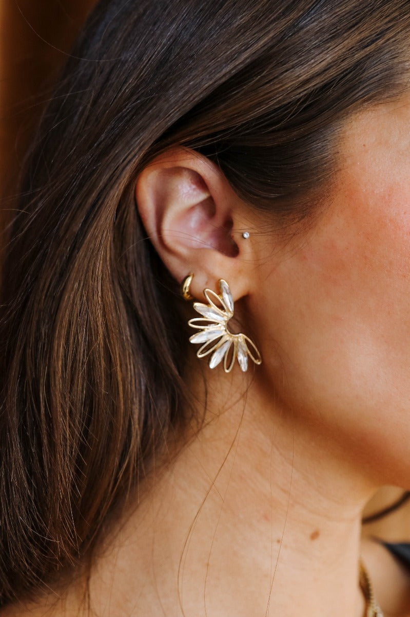 Side view of model wearing the Alondra Gold & Clear Stud Earrings that have half gold flower studs with clear stones.