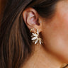Side view of model wearing the Alondra Gold & Clear Stud Earrings that have half gold flower studs with clear stones.