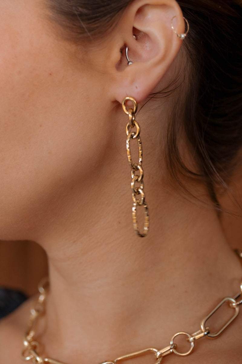 Side view of model wearing the Juliette Gold Chain Link Earrings that have gold dangle hammered chains linked together.