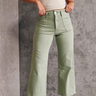 Front view of model wearing the Alexa Sage High-Waisted Wide Leg Pants which features sage denim fabric, two front pockets, two back pockets, front zipper with button closure, belt loops and wide pant legs.