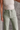 Close up view of model wearing the Alexa Sage High-Waisted Wide Leg Pants which features sage denim fabric, two front pockets, two back pockets, front zipper with button closure, belt loops and wide pant legs.