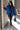 Full body front view of model wearing the Maren Blue Teddy Jacket that has royal blue faux-fur sherpa fabric, tortoise buttons, pockets, a collar, and long sleeves with buttoned cuffs.